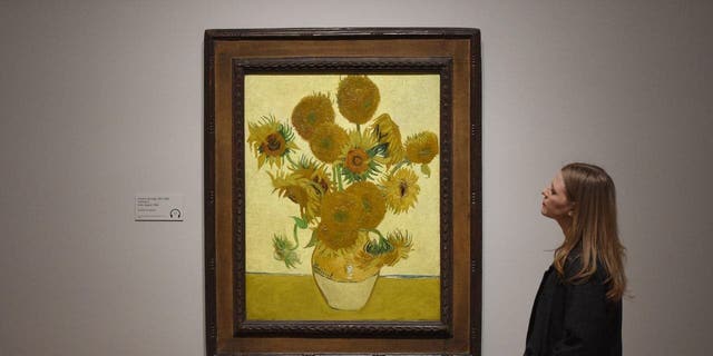 FILE - A woman looks at Vincent van Gogh's Sunflowers painting, March 25, 2019, in London.