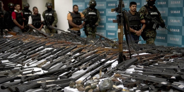 Mexican marines escort five alleged drug traffickers of the Zeta drug cartel in front of an RPG-7 rocket launcher, hand grenades, firearms, cocaine and military uniforms seized to alleged members of the Zetas drug traffickers cartel and presented to press on June 9, 2011, at the Navy Secretaryship in Mexico City.