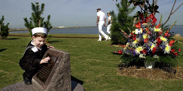 Five-year-old Eathan Costelow touches a part of the USS Cole memorial at Norfolk Naval Base October 12, 2001, in Norfolk, Virginia. Eathan's father, Richard D. Costelow, was one of the 17 sailors killed while onboard the USS Cole during a terrorist attack on October 12, 2000, in Yemen.