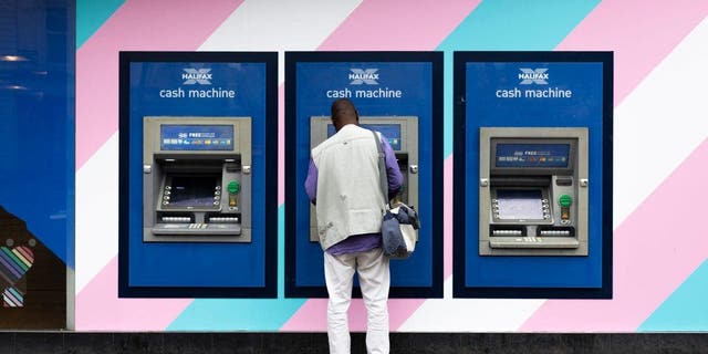 A member of the public makes a withdrawal from an automated teller machine July 14, 2022, in Manchester, United Kingdom.