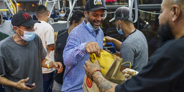 A group of migrants who arrived on a bus from Texas over the summer are given cheeseburgers as they prepare to take a CTA bus to a Salvation Army shelter in Chicago. Another bus left Texas for Chicago on Thursday, Gov. Greg Abbott said.