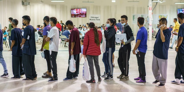 Migrants wait in line to board chartered buses traveling to New York and Chicago at a Welcome Center in El Paso, Texas, US, on Thursday, Sept. 22, 2022. 