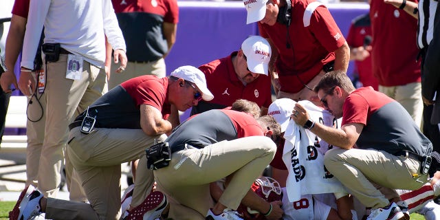 Coaches surround quarterback Dillon Gabriel (8) of the Oklahoma Sooners as he lies on the field after taking a hit from linebacker Jamoi Hodge of the TCU Horned Frogs in the second quarter at Amon G. Carter Stadium Oct. 1, 2022, in Fort Worth, Texas. Hodge was disqualified from the game. 