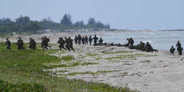 U.S. and South Korean marines take positions after disembarking from a U.S. Marine landing ship during a joint amphibious landing exercise with their Filipino counterparts at a beach facing the South China Sea in San Antonio town, Zambales province, Oct. 7, 2022. 