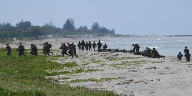 U.S. and South Korean marines take positions after disembarking from a U.S. Marine landing ship during a joint amphibious landing exercise with their Filipino counterparts at a beach facing the South China Sea in San Antonio town, Zambales province, Oct. 7, 2022.
