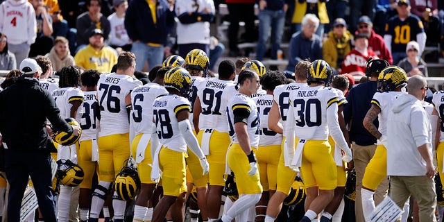 Michigan Wolverines players and coaches watch as medical attention is given to running backs coach Mike Hart after he collapsed on the sideline during a college football game against the Indiana Hoosiers on Oct. 8, 2022 at Memorial Stadium in Bloomington, Indiana. 