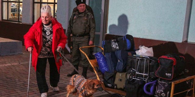 A woman arrived from Kherson leads her dog along a platform for further evacuation into the depths of Russia at the Dzhankoi's railway station in Crimea on Oct. 21, 2022. 
