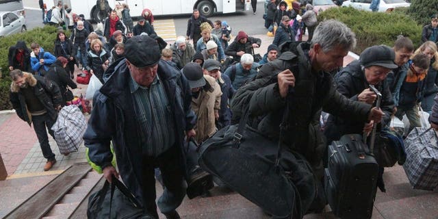 People arriving from Kherson hold their bags as they await further evacuation into the depths of Russia at Dzhankoi Railway Station in Crimea on October 21, 2022. 