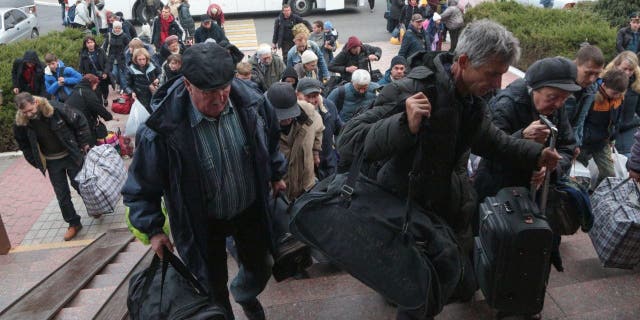 People arriving from Kherson hold their bags as they await further evacuation into the depths of Russia at Dzhankoi Railway Station in Crimea on October 21, 2022. 