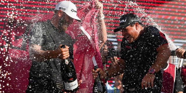 Team Captain Dustin Johnson of 4 Aces GC and Patrick Reid celebrate on the podium after the LIV Golf Invitational - Miami Tag Team Championship round at Trump National Doral Miami on October 30, 2022 in Doral, Florida.
