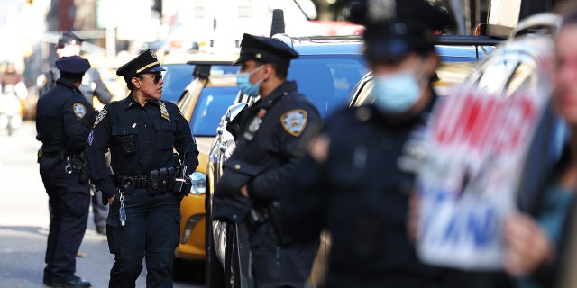 Polizisten stehen Wache, während sich Menschen am 3. November 2021 im City Hall Park in New York City versammeln, um gegen Impfaufträge für Stadtangestellte zu protestieren.