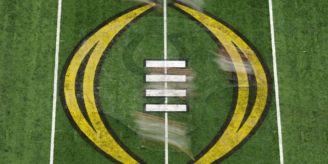 Players run across the 2022 CFP National Championship logo on the field in the first quarter of a game between the Georgia Bulldogs and the Alabama Crimson Tide during the 2022 CFP National Championship Game at Lucas Oil Stadium Jan. 10, 2022, in Indianapolis. 