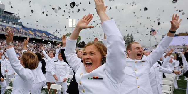 Erin Finley (front, center) of Downingtown, Pennsylvania, and her fellow U.S. Naval Academy graduates throw their hats into the air at the conclusion of their graduation and commissioning ceremony in the academy's Memorial Stadium on May 27, 2022, in Annapolis, Maryland. 