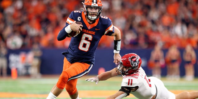 Garrett Shrader, #6 of the Syracuse Orange, runs the ball as Payton Wilson, #11 of the North Carolina State Wolfpack, attempts to tackle Shrader during the third quarter at JMA Wireless Dome on Oct. 15, 2022 in Syracuse, New York.