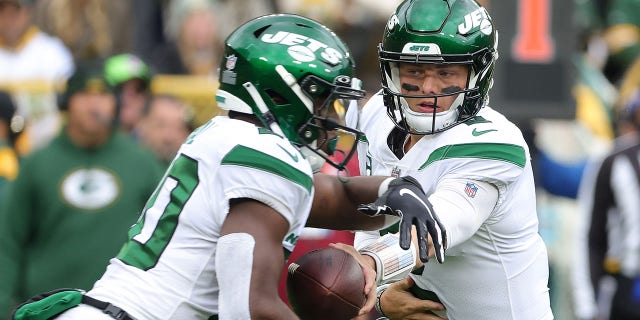 Zach Wilson no. 2 of the New York Jets delivers the ball to Breece Hall No. 20 during a game against the Green Bay Packers at Lambeau Field on October 16, 2022 in Green Bay, Wisconsin. The Jets defeated the Packers 27-10.
