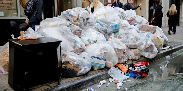 People make their way past trash bags on Oct. 18, 2022 in New York City.