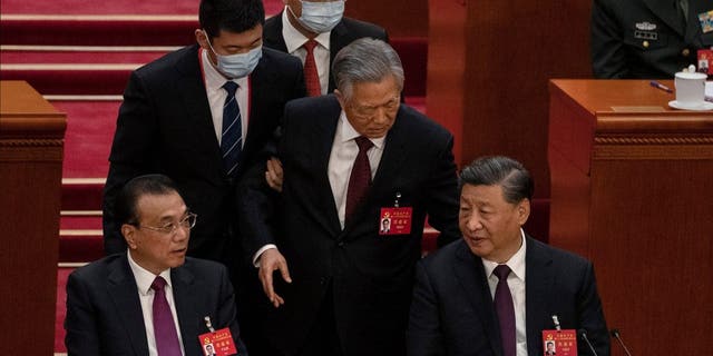 BEIJING, CHINA - OCTOBER 22: Chinese President Xi Jinping and Premier Li Keqiang, left, look on as former President Hu Jintao, centre, speaks to Xi as he is helped to leave early from the closing session of the 20th National Congress of the Communist Party of China, at The Great Hall of People on October 22, 2022 in Beijing, China's Communist Party Congress is concluding today with incumbent President Xi Jinping expected to seal a third term in power. 