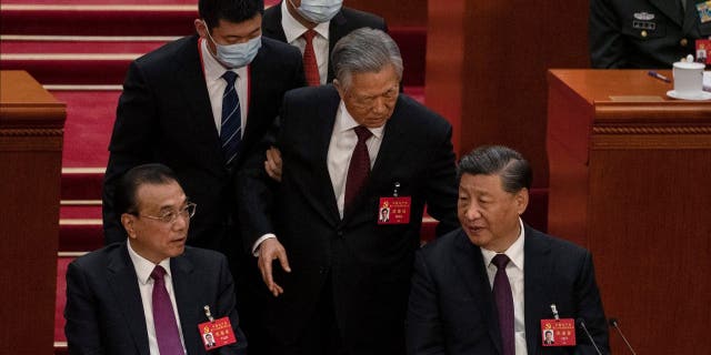 BEIJING, CHINA - OCTOBER 22: Chinese President Xi Jinping and Premier Li Keqiang, left, look on as former President Hu Jintao, centre, speaks to Xi as he is helped to leave early from the closing session of the 20th National Congress of the Communist Party of China, at The Great Hall of People on October 22, 2022 in Beijing, China's Communist Party Congress is concluding today with incumbent President Xi Jinping expected to seal a third term in power.