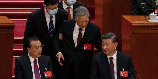 Chinese President Xi Jinping (seat right) and Premier Li Keqiang (left) watch as former President Hu Jintao (center) is escorted away during the closing ceremony of the 20th National Congress of the Communist Party of China on October 22, 2022. seated), in Beijing.