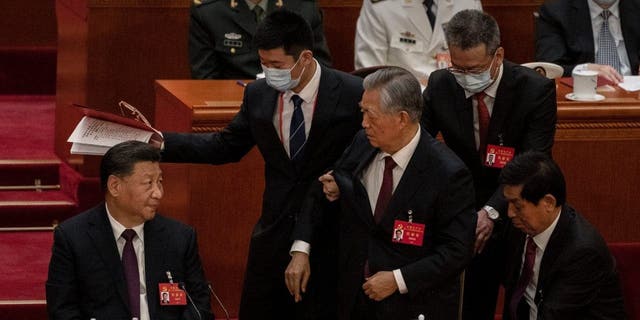 Chinese President Xi Jinping, seated left, looks on as former President Hu Jintao is suddenly escorted away during the closing session of the 20th National Congress of the Communist Party of China, Oct. 22, 2022, in Beijing.