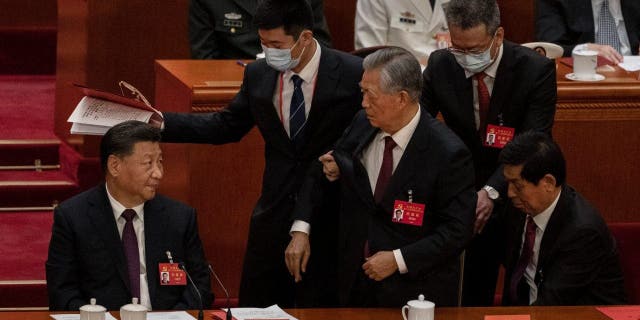 Chinese President Xi Jinping, seated left, looks on as former President Hu Jintao is suddenly escorted away during the closing session of the 20th National Congress of the Communist Party of China, Oct. 22, 2022, in Beijing.