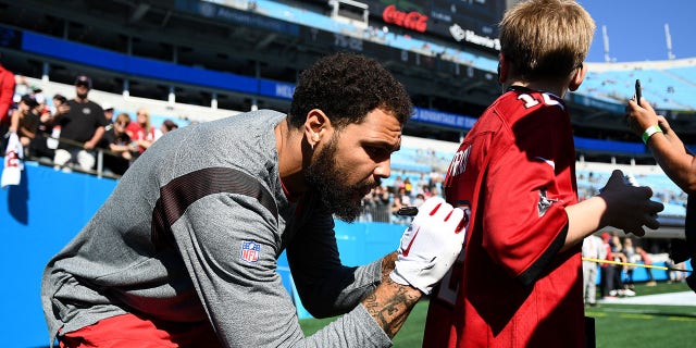 Mike Evans of the Tampa Bay Buccaneers signs a young fan's jersey before the Panthers game at Bank of America Stadium on Oct. 23, 2022, in Charlotte, North Carolina.