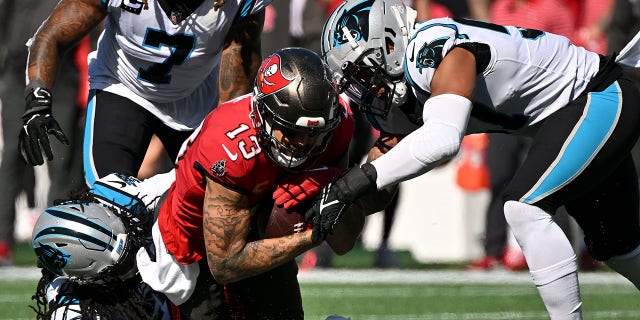 Damien Wilson and Donte Jackson of the Panthers tackle Mike Evans of the Tampa Bay Buccaneers on Oct. 23, 2022, in Charlotte, North Carolina.
