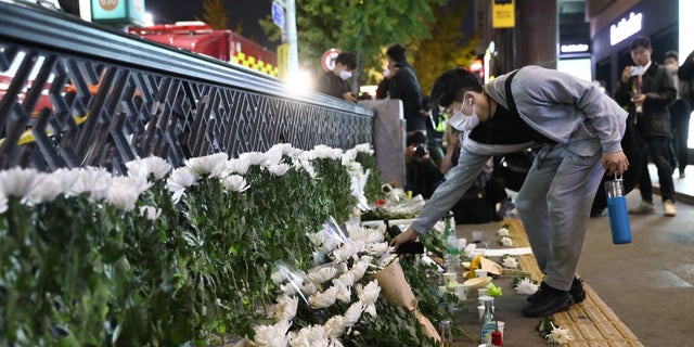 A man lays flowers as he cries on the way of a deadly stampede during a Halloween festival on October 30, 2022 in Seoul, South Korea. (Photo by Chung Sung-Jun / Getty Images)