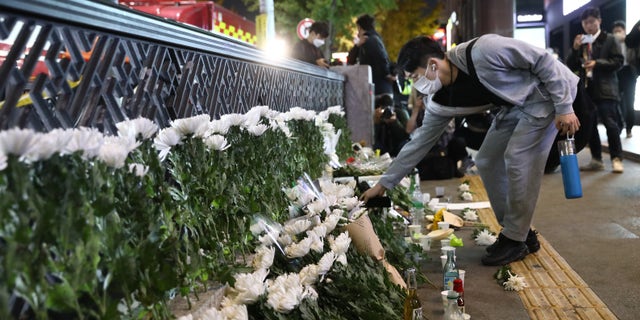 A man lays flowers as he cries on the way of a deadly stampede during a Halloween festival on October 30, 2022 in Seoul, South Korea. (Photo by Chung Sung-Jun / Getty Images)