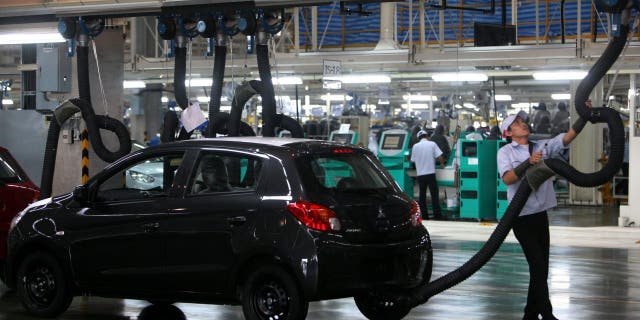 FILE - A Mitsubishi Motors Corp. worker operates equipment on the production line of the Mirage vehicle at the company's plant in Laem Chabang, Thailand.