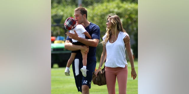 New England Patriots quarterback Tom Brady carries his son Benjamin as he walks off the practice field with Gisele Bundchen at the end of practice. (John Tlumacki/The Boston Globe via Getty Images)