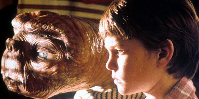 E.T. looking out of a window with Henry Thomas in a scene from the film 'E.T. The Extra-Terrestrial', 1982. 