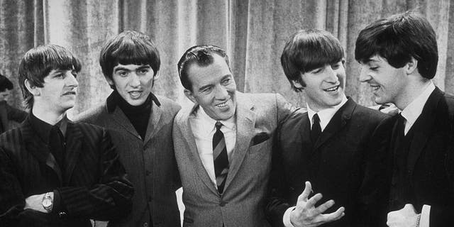 American television host Ed Sullivan smiles while standing with the Beatles on the set of his television variety series, New York, Feb. 9, 1964. Left to right, Ringo Starr, George Harrison, Sullivan, John Lennon, Paul McCartney.