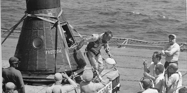 American sailor and astronaut Alan B. Shepard (1923-1998) as he emerges from the Freedom 7 space capsule onto the flight deck of the recovery carrier USS Lake Champlain (CV-39) after his historic Mercury 3 flight, Atlantic Missile Range, May 5, 1961. Shepard became the first American in space and also became the first human to return to Earth in his spacecraft, as Soviet cosmonauts had parachuted during re-entry.