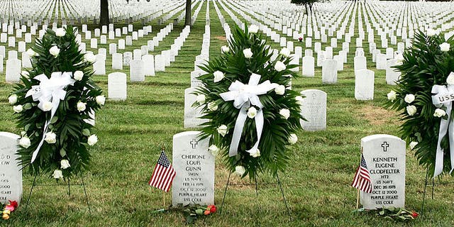 Wreaths are laid next to the tombstones of victims of the USS Cole attack, Cherone Gunn of Virginia Beach, Virginia, left, and Kenneth Clodfelter of Richmond, Virginia, during a ceremony to mark the fifth anniversary of the attack that took the lives of 17 U.S. Navy personnel, on October 12, 2005, at the Arlington National Cemetery in Arlington, Virginia. 