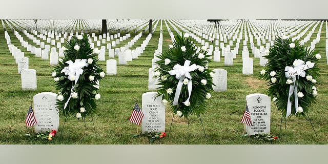 Wreaths are laid next to the tombstones of victims of the USS Cole attack, Cherone Gunn of Virginia Beach, Virginia, left, and Kenneth Clodfelter of Richmond, Virginia, during a ceremony to mark the fifth anniversary of the attack that took the lives of 17 U.S. Navy personnel, on October 12, 2005, at the Arlington National Cemetery in Arlington, Virginia.