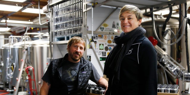 Alchemist brewery owners John and Jen Kimmich pose for a portrait while sitting on stacks of Heady Toppers in Waterbury, Vermont.  Heady Topper, a hazy 