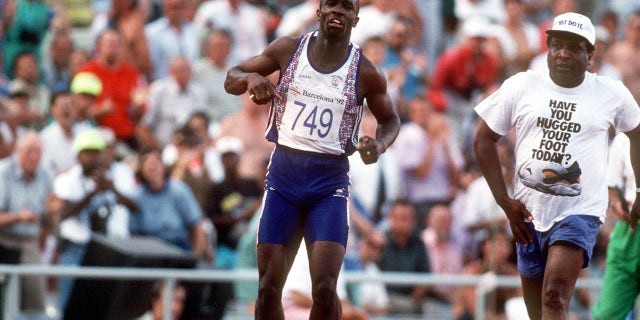 Great Britain's Derek Redmond, left, limps around the track toward the finish line after tearing his hamstring as his dad Jim races after him to offer help and consolation.