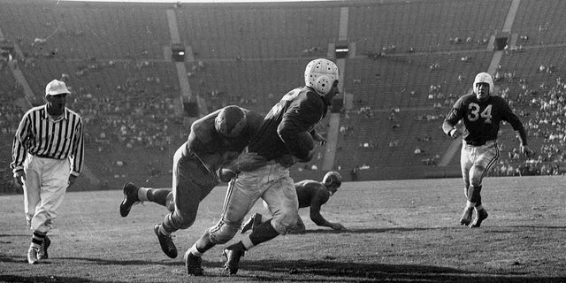 Halfback Charley Trippi of the Chicago Cardinals tries to avoid being tackled by Rams defender Pat Harder (34) in a 27-to-22 win over the Los Angeles Rams on October 31, 1948, at Los Angeles Memorial Coliseum in Los Angeles, California. 