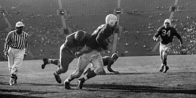 Halfback Charley Trippi of the Chicago Cardinals tries to avoid being tackled by Rams defender Pat Harder (34) in a 27-to-22 win over the Los Angeles Rams on October 31, 1948, at Los Angeles Memorial Coliseum in Los Angeles, California. 