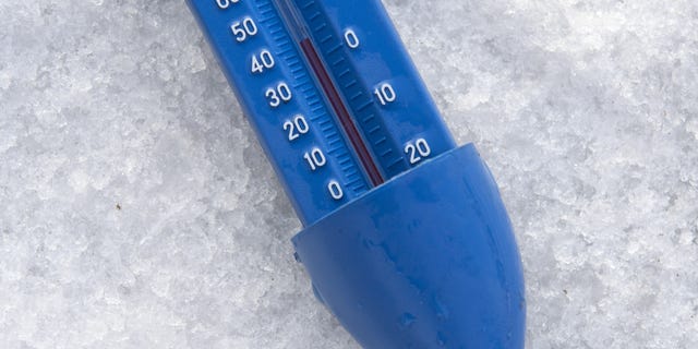 A thermometer shows a reading of 3.5-4 degrees Celsius taken from the ice-cold water at Highgate Men's Bathing Pond, in north London on December 12, 2017, at sunrise on a freezing winter morning.