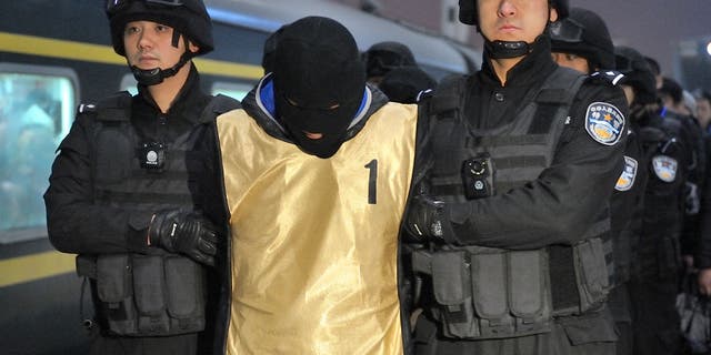 Chinese telecom fraud suspects, deported from Guangzhou, are escorted by police off a train after arriving at the Harbin west station January 15, 2018 in Harbin city of China. Police deported 37 Chinese telecom fraud suspects to Qiqihar. (Photo by Tao Zhang/Getty Images)