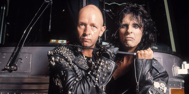 Rob Halford, left, and Alice Cooper pose in front of a tour bus, circa 1990s.