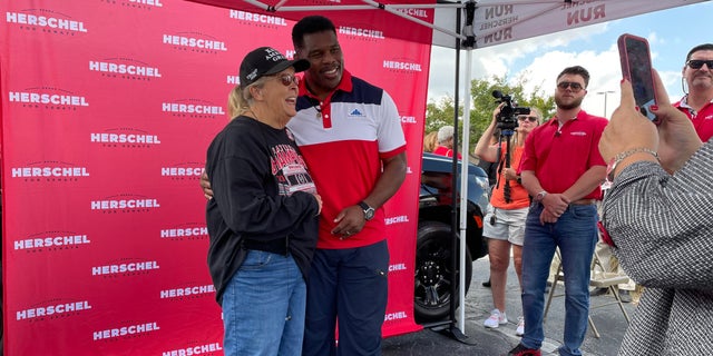 Republican Senate nominee in Georgia Herschel Walker takes photos with supporters, at a campaign event in Carrollton, Georgia on Oct. 12, 2022