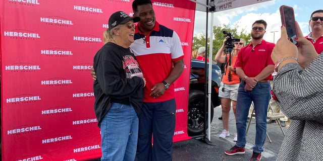 Republican Senate nominee in Georgia Herschel Walker takes photos with supporters, at a campaign event in Carrollton, Georgia on Oct. 12, 2022