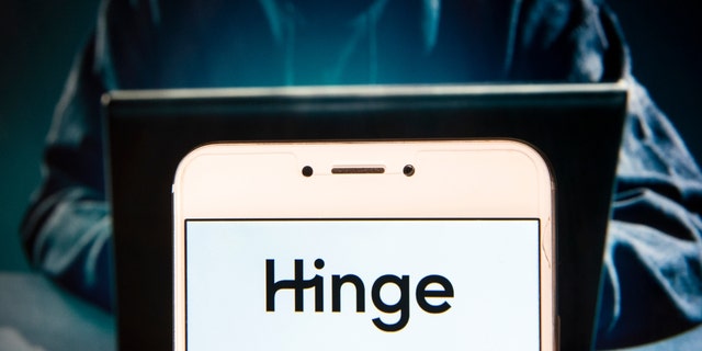 Hong Kong, China - 12/02/2018: In this photo illustration, the online dating app Hinge logo can be seen displayed on an Android mobile device with a hacker in the background. 