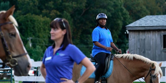 Dionne Williamson, right, of Patuxent River, Maryland, participates in a riding lesson at Cloverleaf Equine Center in Clifton, Virginia, Tuesday, Sept. 13, 2022, as Equine Coordinator Clarice Gutman, left, works with another rider. After finishing a tour in Afghanistan in 2013, Williamson, experienced disorientation, depression, memory loss and chronic exhaustion. "It’s like I lost me somewhere," said the Navy lieutenant commander. After fighting for years to get the help she needed, she eventually found stability through a monthlong hospitalization and a therapeutic program that incorporates horseback riding.