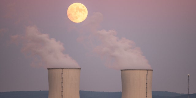 TRILLO, GUADALAJARA, SPAIN - 2021/10/19: An almost full moon of October, known as Hunter's Moon, rises over the cooling towers of the Trillo Nuclear Power Plant.