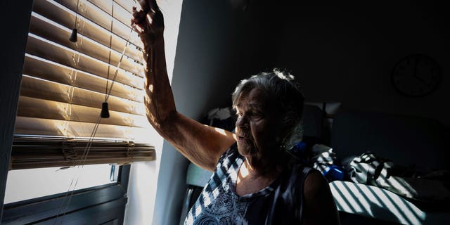 Barbara Wasko looks out the window of the sanctuary of the Southwest Baptist Church in Fort Myers, Fla., on Sunday, Oct 2, 2022. She took refuge inside the church when Hurricane Ian swept through Southwest Florida. (AP Photo/Robert Bumsted)