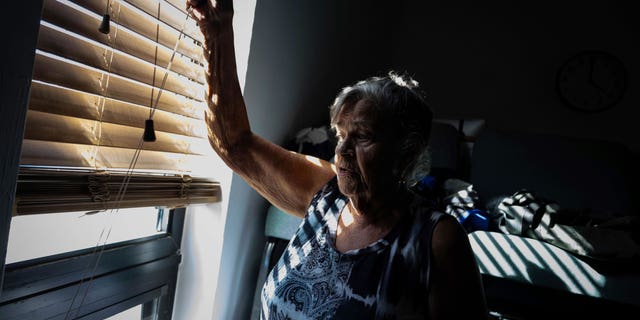 Barbara Wasko looks out the window of the sanctuary of the Southwest Baptist Church in Fort Myers, Fla., on Sunday, Oct 2, 2022. She took refuge inside the church when Hurricane Ian swept through Southwest Florida. (AP Photo/Robert Bumsted)